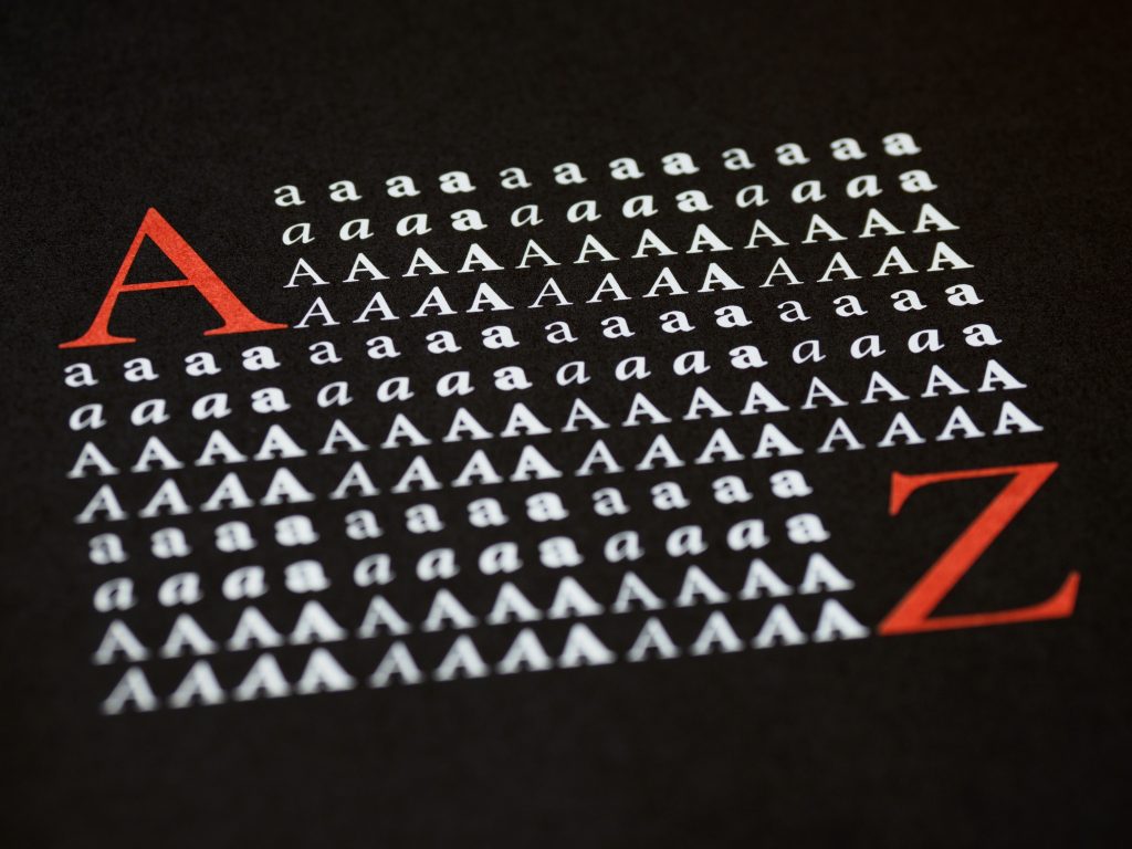 Rows of the letter A in different typefaces printed on black paper, framed by a large red A and Z.