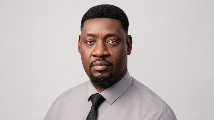 Portrait of Franklyn James in a grey shirt and black tie